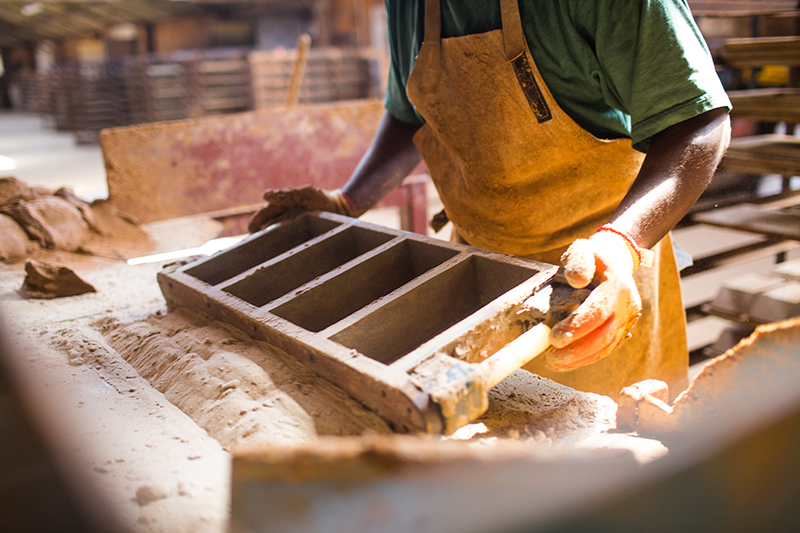 An HG Matthews brickmaker preparing the mould with sand ready to add the clay in the process of making handmade bricks